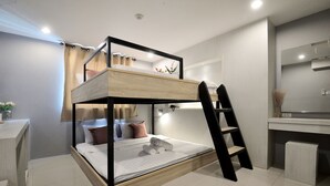 A bunk bed with a desk and ladder, a mirror, and a small bathroom area. - De Lux Bangkok Hotel (Bangkok)
