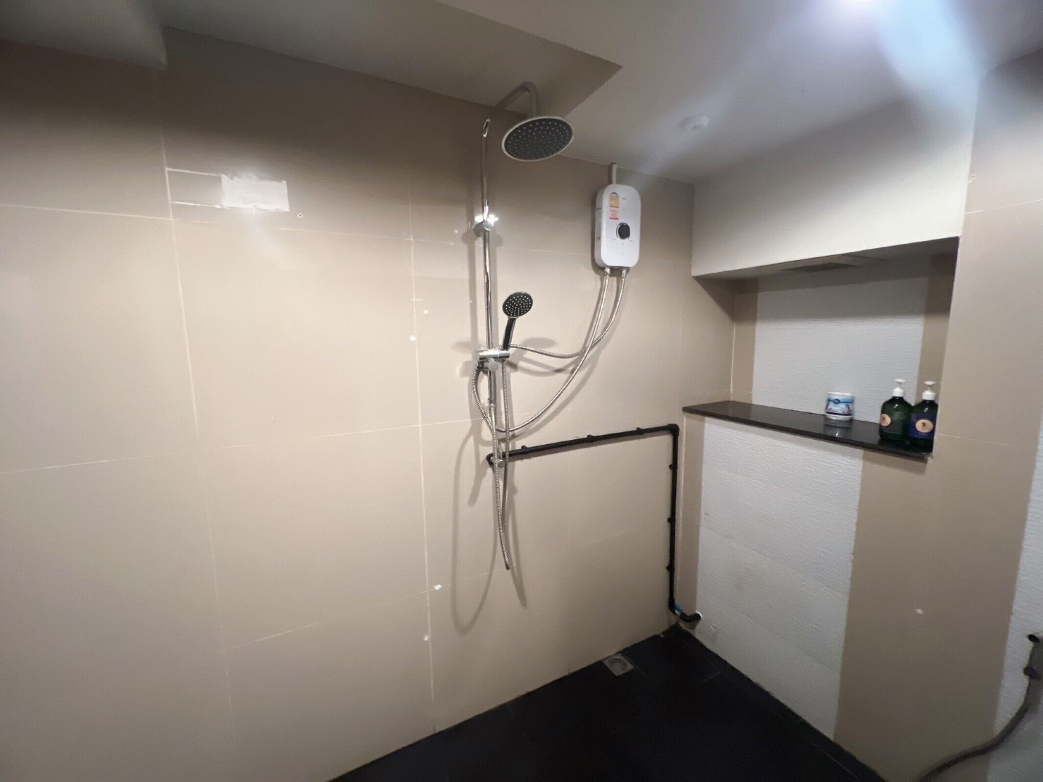 A bathroom with a shower, a towel rack, and a shelf with toiletries.