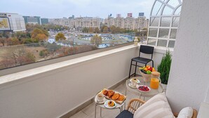 Ein Balkon mit Frühstückstisch, Stuhl und Blick auf eine Stadtansicht.