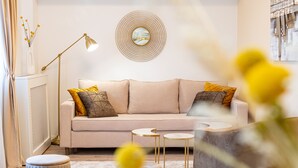Ein modernes Wohnzimmer mit einem beige Coloured Sofa, zwei runden Beistelltischen und einer Stehlampe.