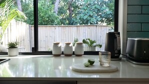 A kitchen counter with a coffee maker, a glass, and three small jars with plants. - Combi's Cove, Byron beachside oasis - NEW listing specials - Enquire Now. (Suffolk Park)