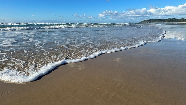 A beach with waves lapping onto the shore, a clear sky, and distant land. - Combi's Cove, Byron beachside oasis - NEW listing specials - Enquire Now. (Suffolk Park)