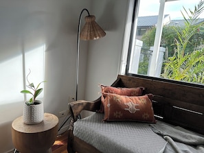 Um quarto acolhedor com um banco de madeira, uma planta em vaso e um abajur.