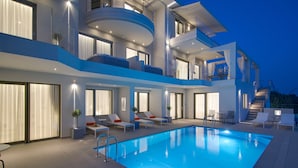 A modern multi-story building with a swimming pool, outdoor seating, and a staircase leading to the upper levels.