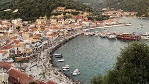 A coastal town with a marina, buildings with red-tiled roofs, and a hilly backdrop.