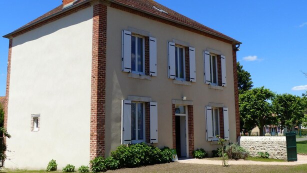 A two-story building with a brick chimney, white exterior walls, and multiple windows with shutters. - Quiet and spacious cottage in the countryside (Fourilles)