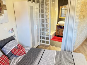 Ein Schlafzimmer mit Bett, Schrank, Badezimmer mit Dusche und einem roten Teppich.