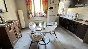 Een kleine keuken met een eettafel, stoelen en basisapparatuur.