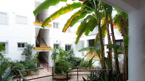 Um pátio com escadaria, plantas em vasos e um edifício com varandas e janelas.
