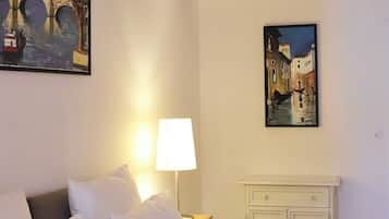 Une chambre d’hôtel avec un grand lit, une table de chevet avec une lampe et deux tableaux accrochés aux murs.