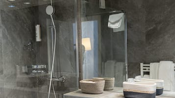 A modern bathroom with a glass-enclosed shower, a large mirror, and a white sink.