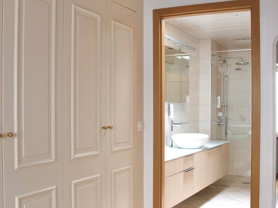 Un baño moderno con cabina de ducha de vidrio, lavamanos blanco y tocador de madera.