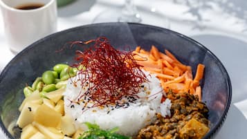A meal with rice, vegetables, and a drink on a table.