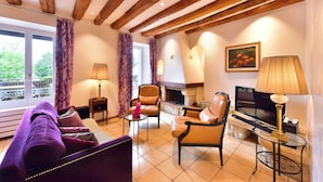 Ein gemütliches Wohnzimmer mit Kamin, Ledersofas und Fernseher.