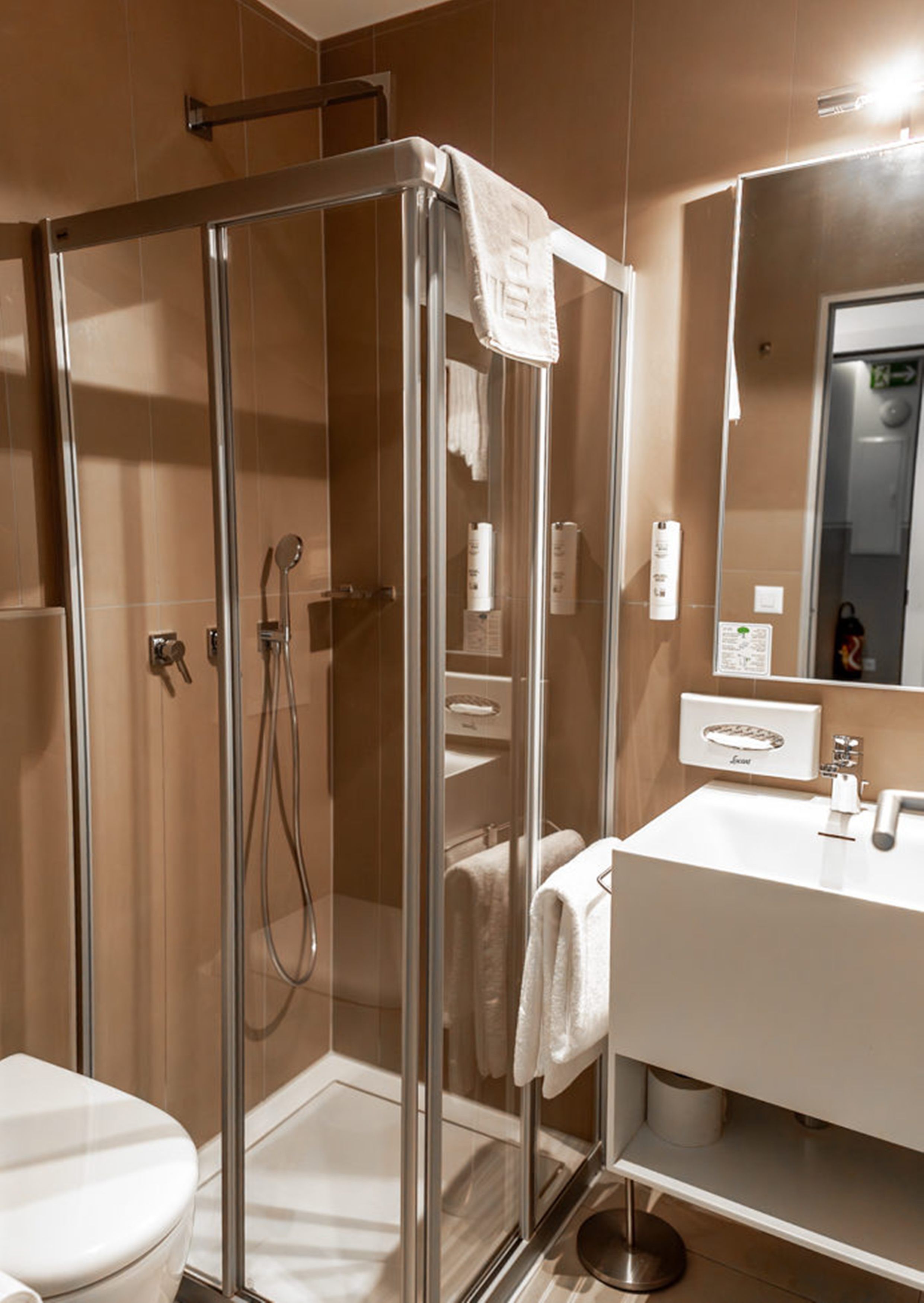 Ein modernes Badezimmer mit einer Duschkabine, einem weißen Waschbecken und einem großen Spiegel.