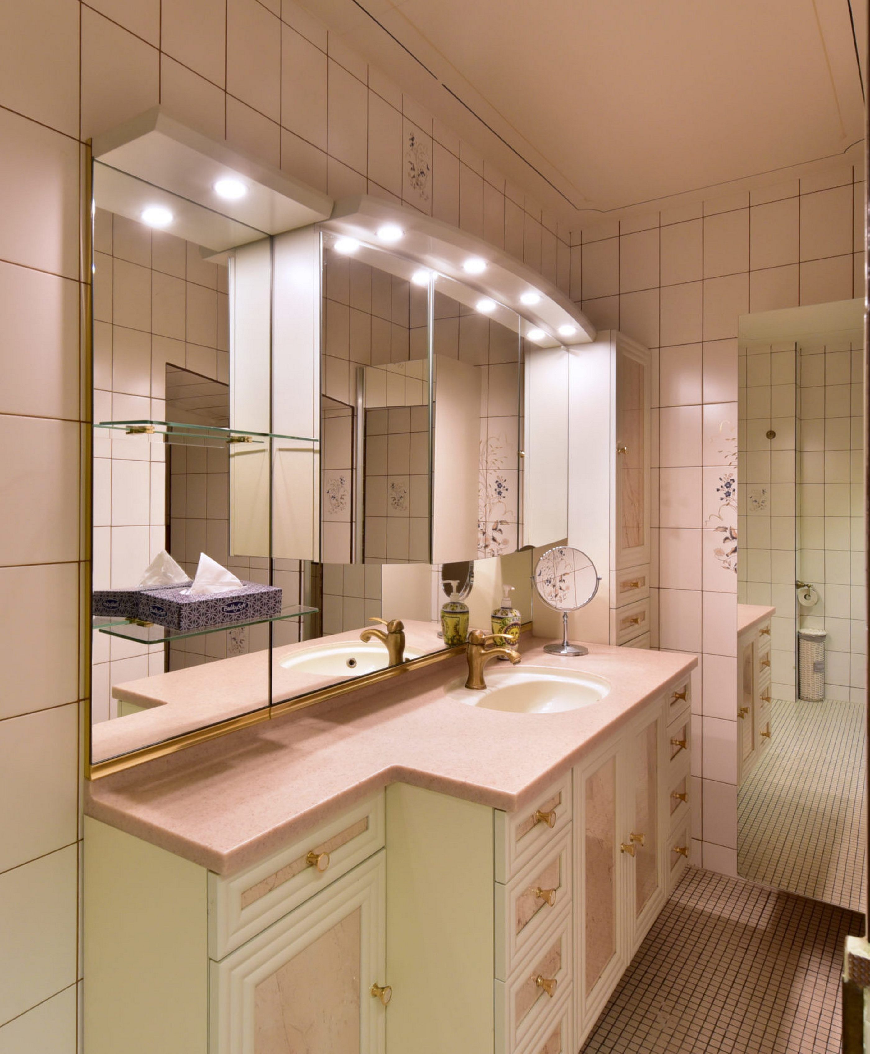 A modern bathroom with a large vanity, a double sink, and a large mirror with lights.