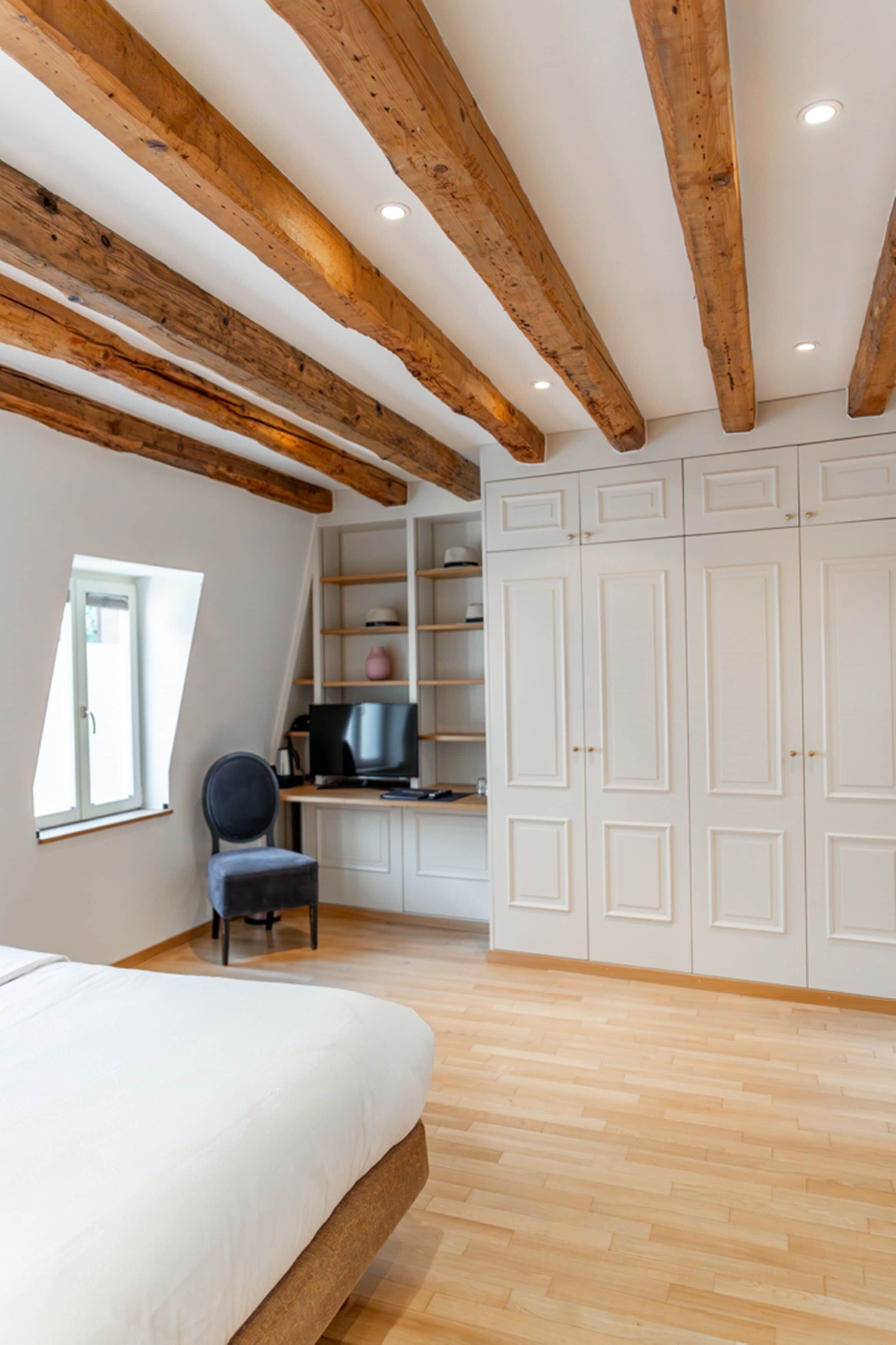 Quarto com cama, escrivaninha com computador, cadeira e armários embutidos.