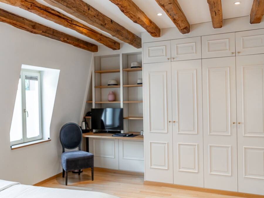 Un dormitorio con cama, escritorio con computadora, silla y armarios empotrados.