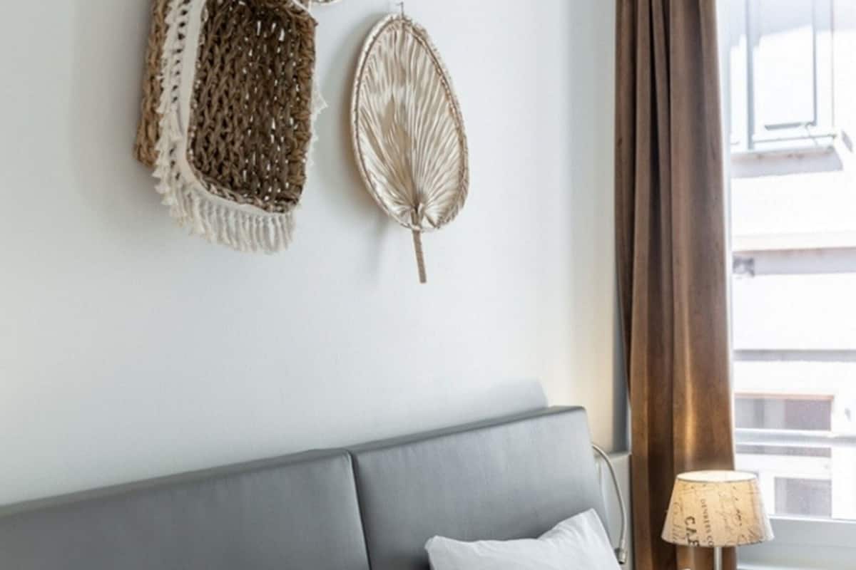 A hotel room with a grey headboard, white bedding, and decorative wall art.