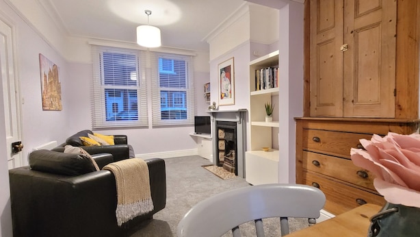 A living room with a fireplace, a bookshelf, and a dining area with a table and chairs. - 2 Bed Holiday Home with on-street parking and river walks (York)
