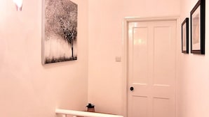 A hallway with a white door, a painting, and a staircase with a white railing. - 2 Bed Holiday Home with on-street parking and river walks (York)