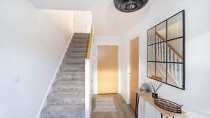 A staircase leading to a door, a wooden console table with a mirror, and a radiator.