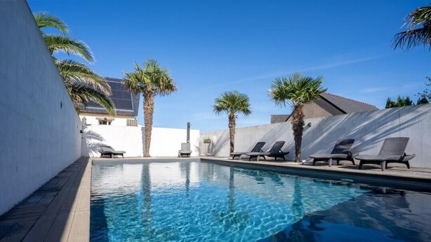 A swimming pool with lounge chairs and palm trees. - House facing the sea, with swimming pool and SPA
OMAHA GITES (Vierville-sur-Mer)