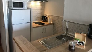 Eine kleine Küche mit Kühlschrank, Mikrowelle, Spüle und Kaffeemaschine.