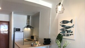 Eine kleine Küche mit Mikrowelle, Kaffeemaschine und einer Pendelleuchte.