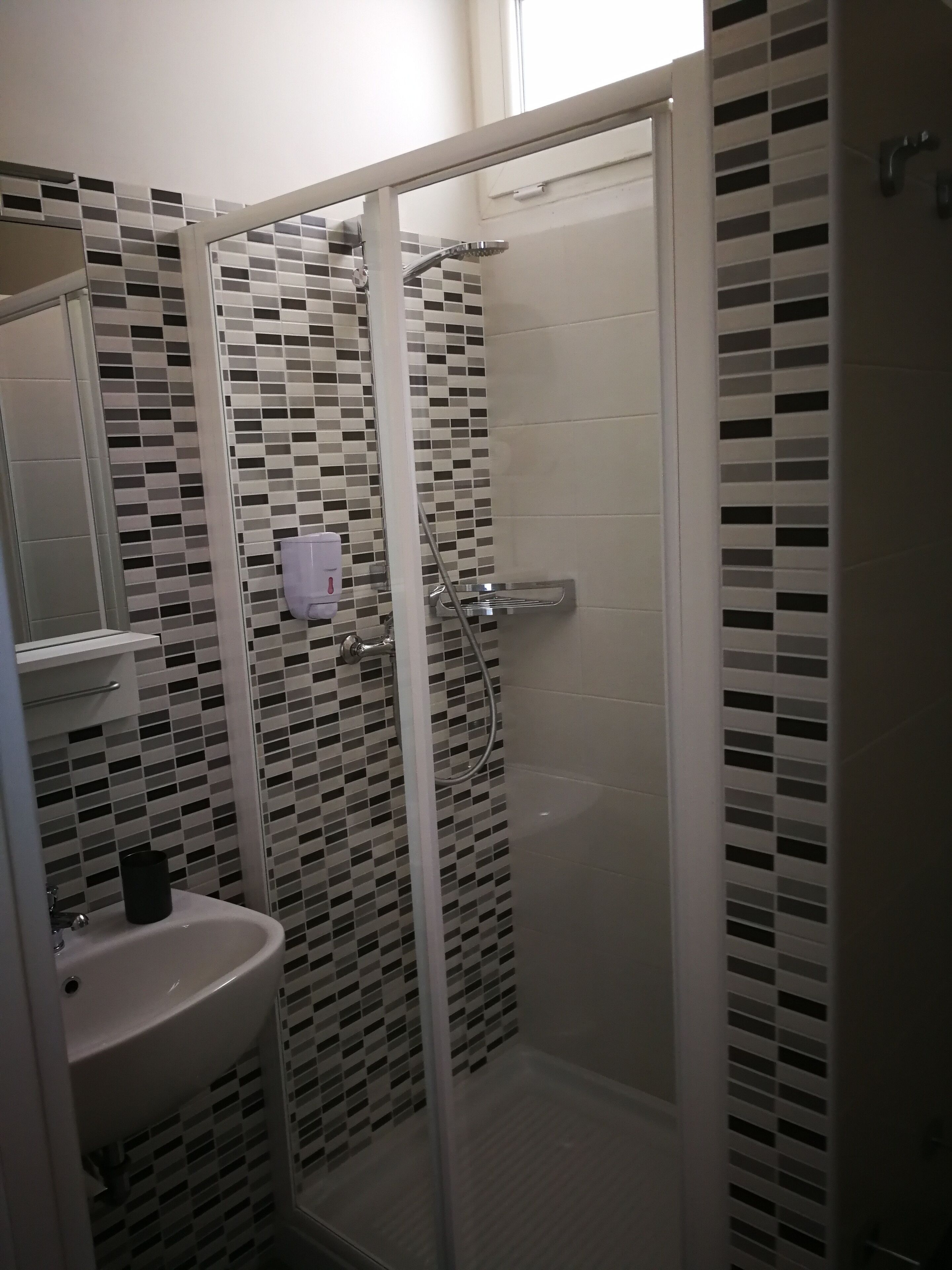 A bathroom with a glass-enclosed shower, a white sink, and a tiled backsplash.