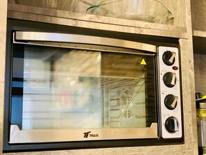 A THULOS microwave oven with a glass door, a digital display, and multiple control knobs.