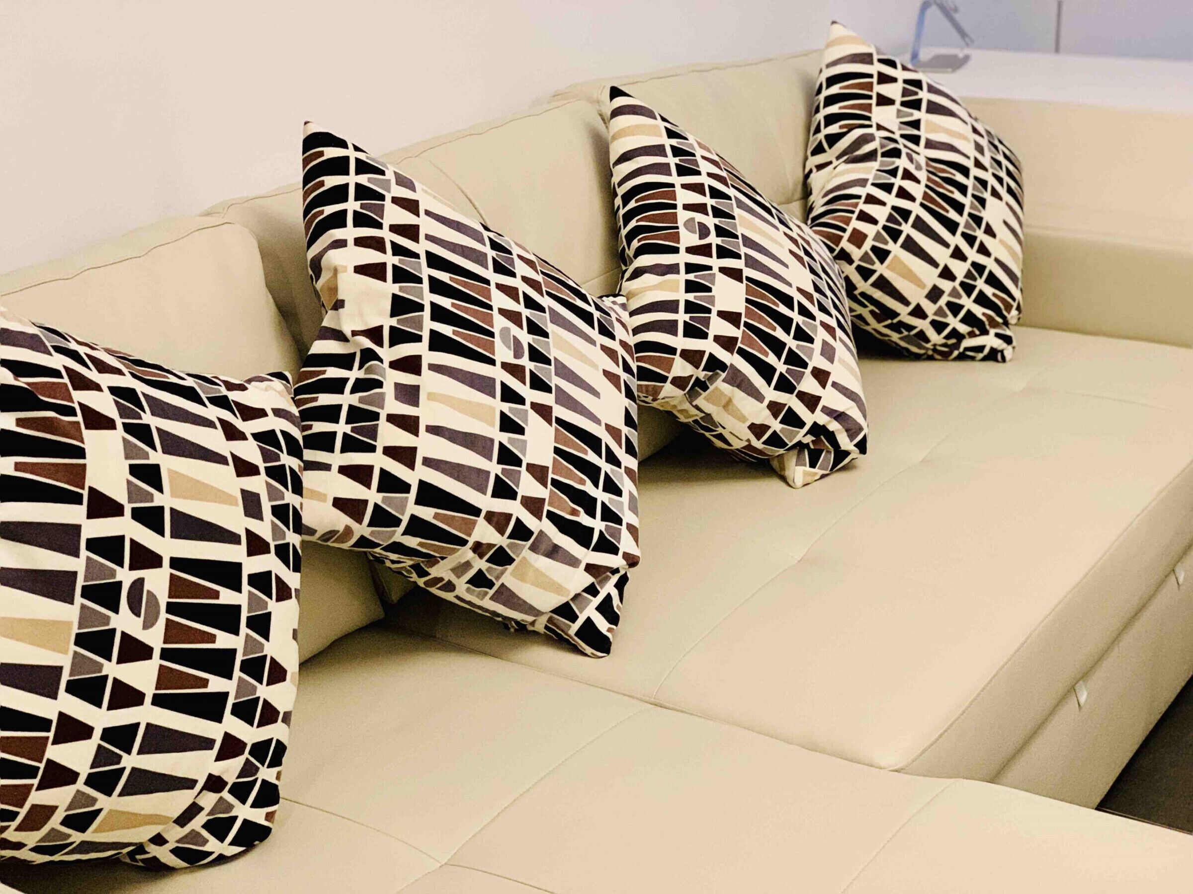 Ein beiges Sofa mit geometrisch gemusterten Kissen.