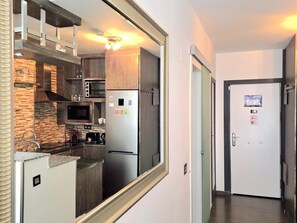 Eine moderne Küche mit einem Edelstahl-Kühlschrank, einer Mikrowelle und einem Herd, einem großen Spiegel und einer Tür mit einem 'NO Smoking'-Schild.