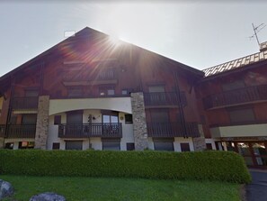 A multi-story building with a prominent balcony on the second floor, a stone base, and a large glass entrance.