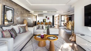 A modern living room with a sofa, two side tables, and a dining area in the background. - Sweet Inn - Villa Alexandra (Cannes)