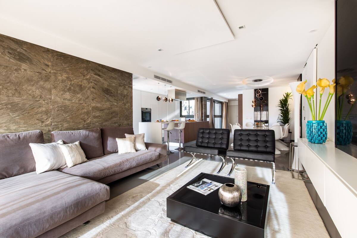 A modern living room with a sectional sofa, a black leather chair, and a coffee table.