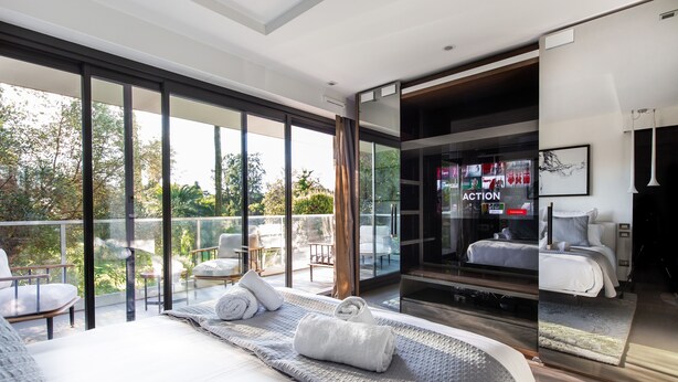 A modern bedroom with a large bed, a glass door leading to a balcony, and a view of the outdoors. - Sweet Inn - Villa Alexandra (Cannes)