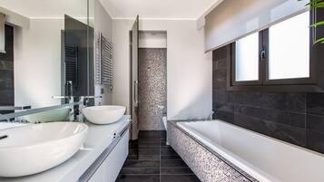 Une salle de bain moderne avec deux grands lavabos blancs, une baignoire sur pieds et une douche à l’italienne.