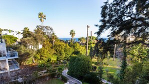A residential area with a curved driveway, lush greenery, and a view of the sea. - Sweet Inn - Villa Alexandra (Cannes)