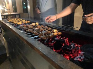 En grill med spyd fyldt med kød og grøntsager, der bliver stegt over kul.