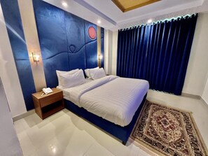 Une chambre à coucher avec un grand lit, une table de chevet, un téléphone fixé au mur et un tapis à motifs.