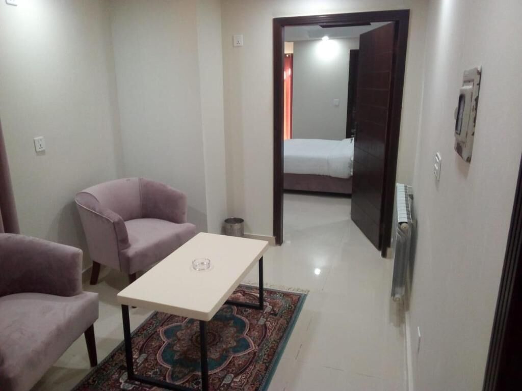 A small, well-lit room with a bed, a table, and two chairs.