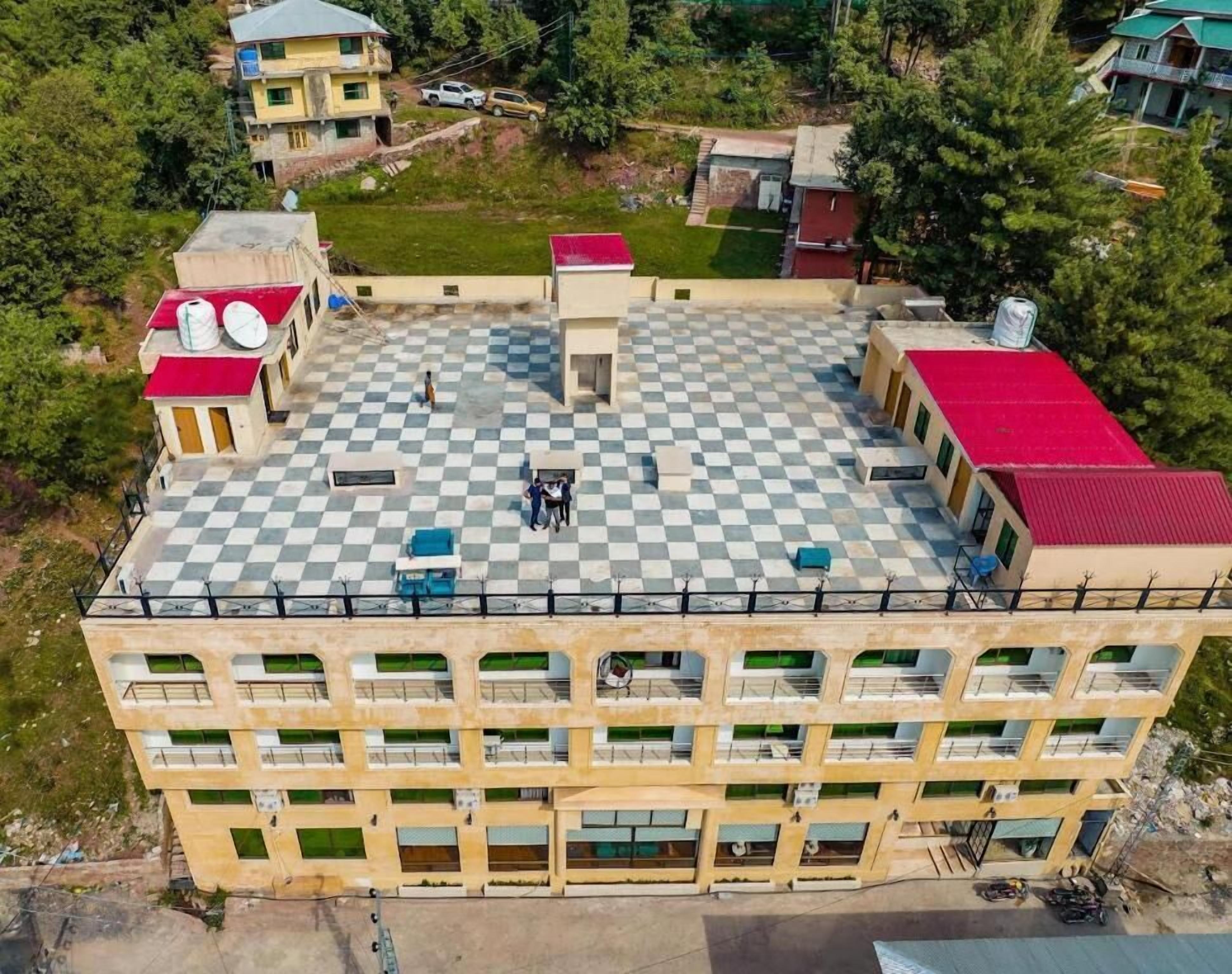 A multi-story building with a checkered roof, multiple balconies, and a central courtyard.