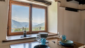 A dining area with a view of mountains through a large window. - Small rustic dream in a quiet location with a view of the mountains (Indemini)