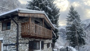 A stone building with a wooden balcony, a bench, and a snow-covered pathway. - Small rustic dream in a quiet location with a view of the mountains (Indemini)