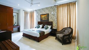 A hotel room with a bed, a desk, a chair, and a ceiling fan. - Lime Tree Hotel Sushant Lok Gurgaon  (Gurugram)