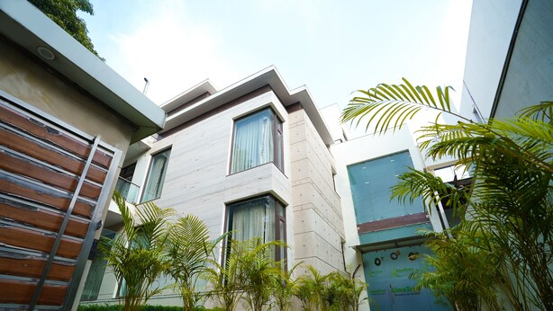 A modern building with a flat roof, large windows, and a well-maintained lawn with potted plants. - Lime Tree Hotel Sushant Lok Gurgaon  (Gurugram)