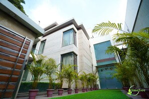 Un edificio moderno con techo plano, ventanas amplias y un césped bien cuidado con plantas en macetas.