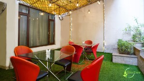 A conference room with a glass table, red chairs, a bamboo ceiling, and a small garden area. - Lime Tree Hotel Sushant Lok Gurgaon  (Gurugram)