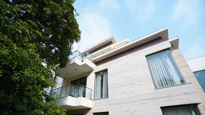 A modern building with a balcony, large windows, and a tree in the foreground. - Lime Tree Hotel Sushant Lok Gurgaon  (Gurugram)